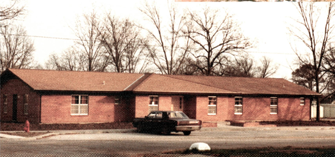 Color photo of Library in 1974 with brown 1967 Plymouth Valiant parked in front  